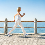 A woman jogging outdoors along a seaside boardwalk.